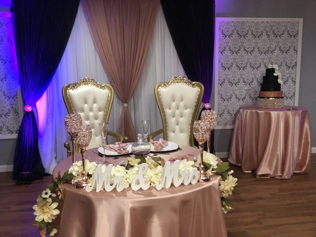 mr and mrs signs on small round table with satin tablecloth and large white chairs